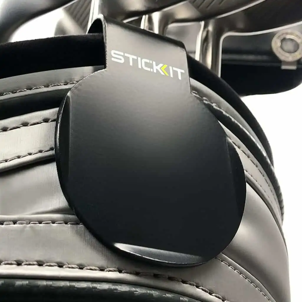STICKIT Magnetic Golf Landing Pad is round and attaches to the side of a golf bag.  STICKIT label is written on it. We consider it one of the best accessories for golf push carts.