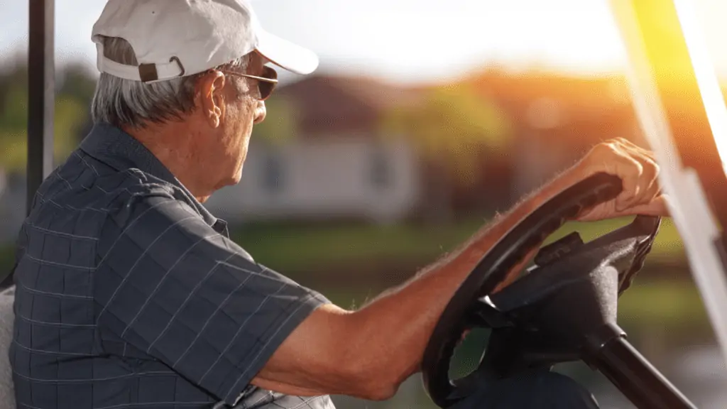 photo showing golfer playing golf with prescription glasses as he looks into the distance from his golf cart to the next hole, holding the steering wheel.  Golf glasses see the ball better.