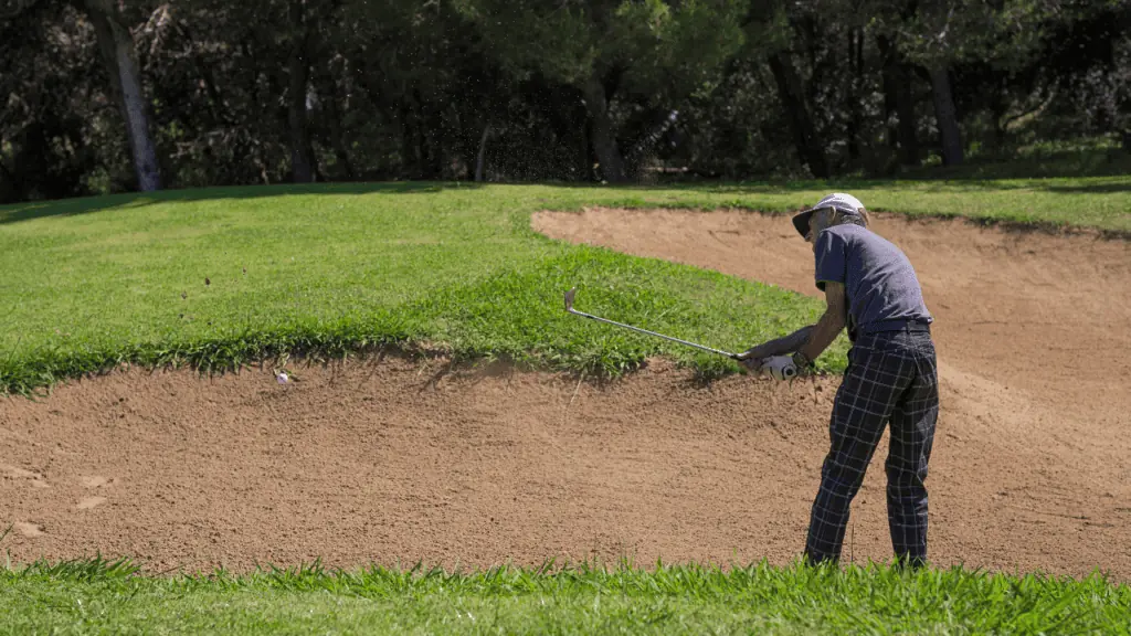 older senior golfer hitting out of a bunker with his sand wedge