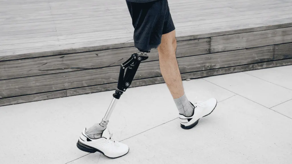 showing a man with prosthetic right leg walking with white golf shoes on.