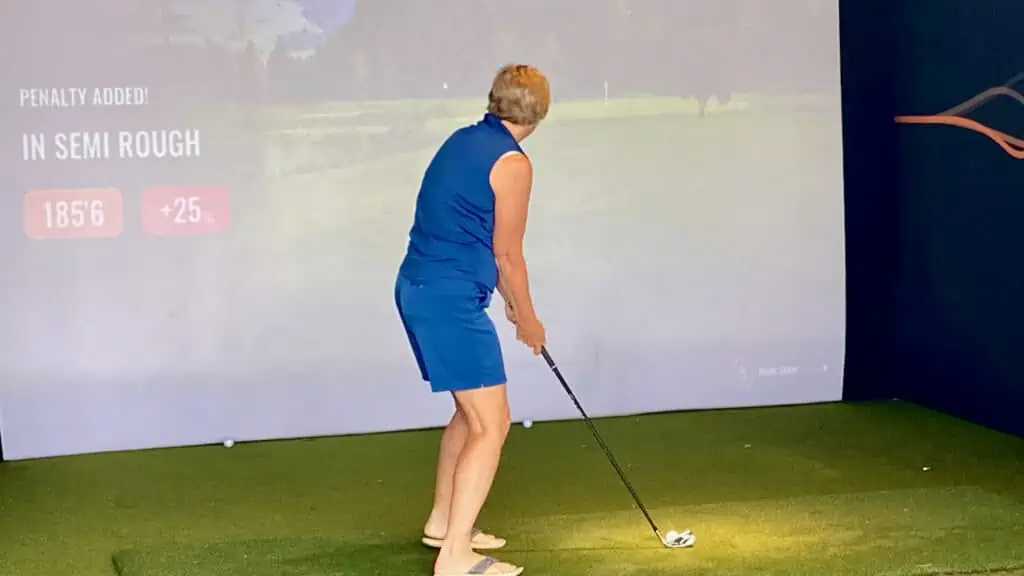 showing a lady senior golfer and the best online golf lessons on a golf simulator.  