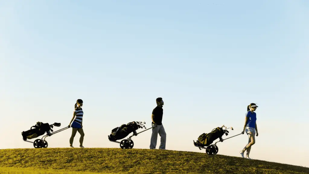 Showing three friends golfing together with their push carts in the distance on a hill 