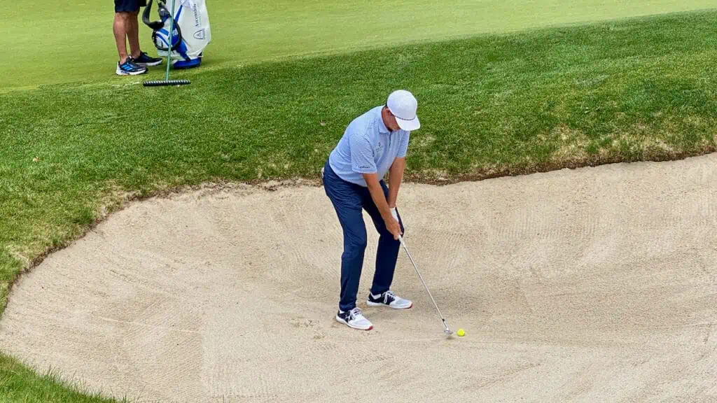 PGA Tour golfer hitting his golf wedge out of a sand trap or bunker.