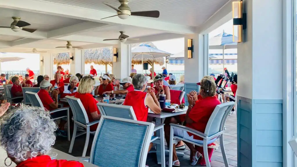 Making friends is one of the benefits of USGA Senior Amateur Golf showing a ladies golf group eating lunch after their golf tournament - everyone is dressed in red. 
