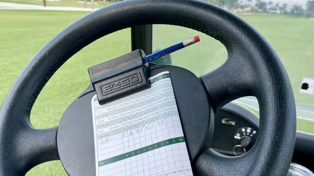 Golfweek Senior Am Tour score card shown in a close up on a golf cart wheel.
