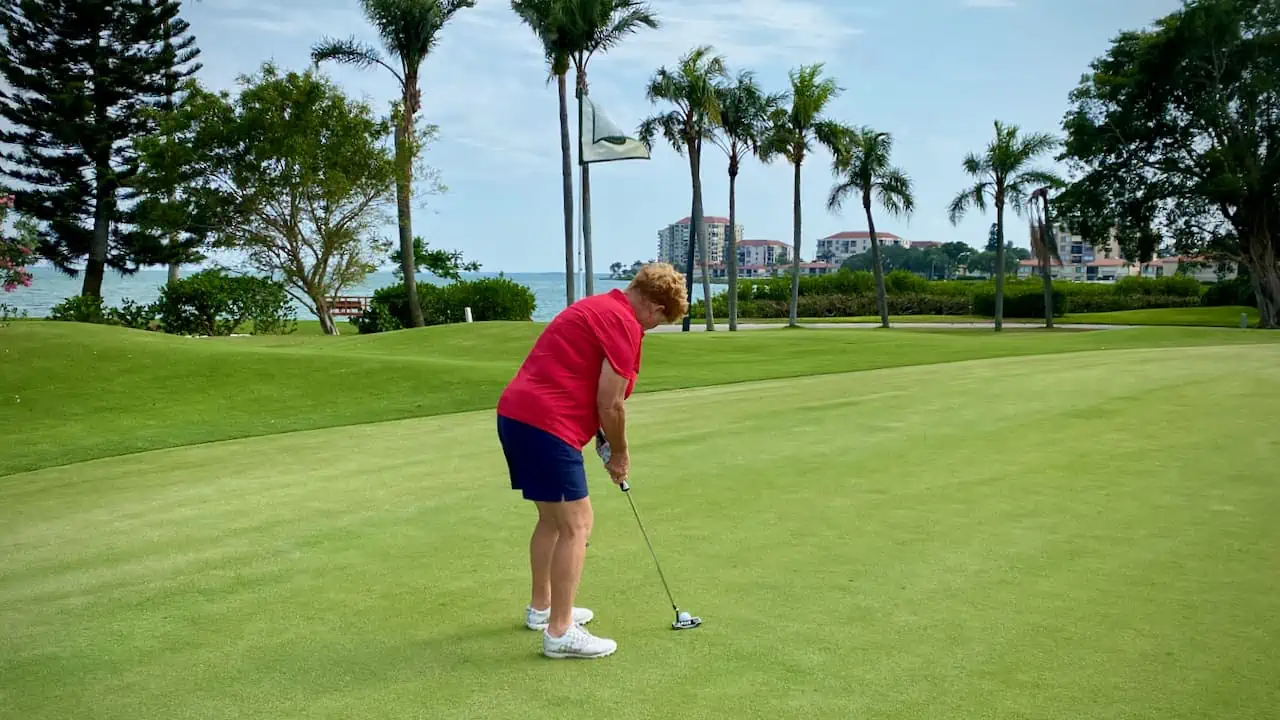senior golfer practicing her putting stroke.