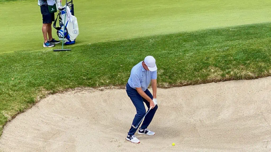 senior tour golfer stuck in a bunker trying to hit out with his golf wedge.