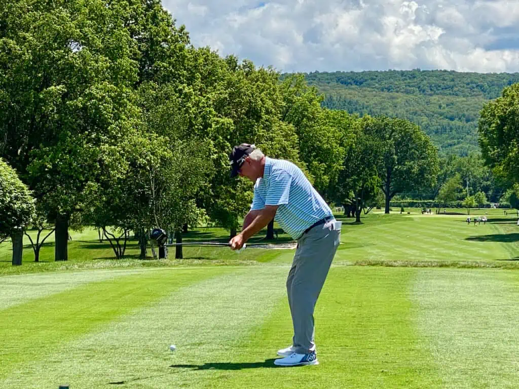 Tall Man golfing in NY.  He is hitting his driver from the tee box.
