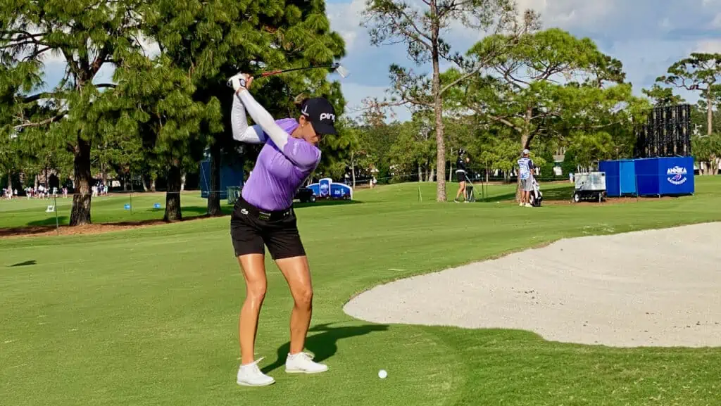 showing a lady golfer hitting her golf wedge