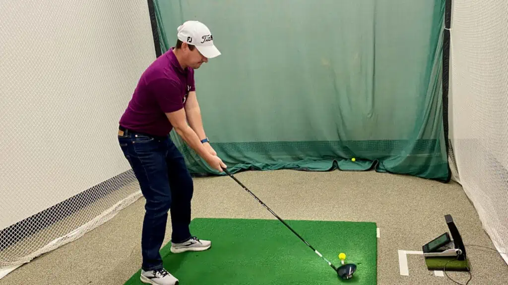 Shorter golfer testing golf clubs with a golf fitter with senior golf source at an indoor golf simulatorr