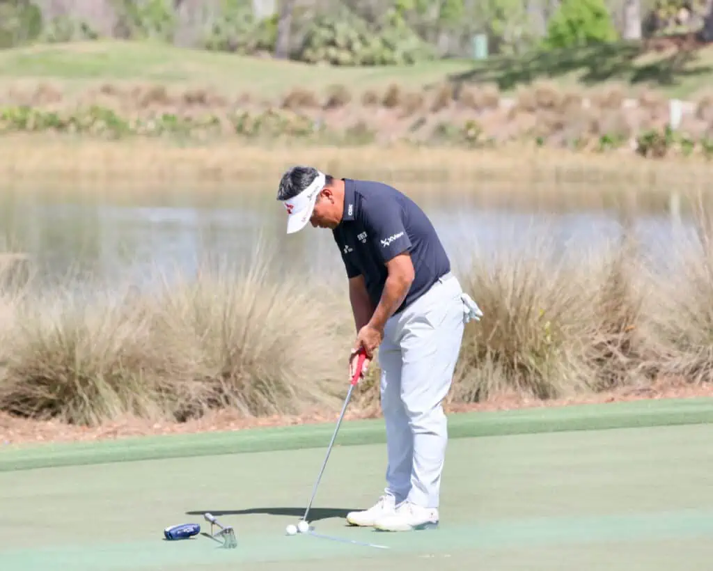 Odyssey White Hot OG Seven Putter on the ground next to KJ. Choi as he practices with another putter.