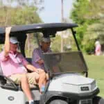 Steve Alker riding in a golf cart with his caddie at the Chubb Classic.
